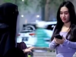 Seorang wanita bercadar memaksa pengunjung wanita yang ada di tengah keramaian dan tampak berpakaian seksi agar mau menutup auratnya.