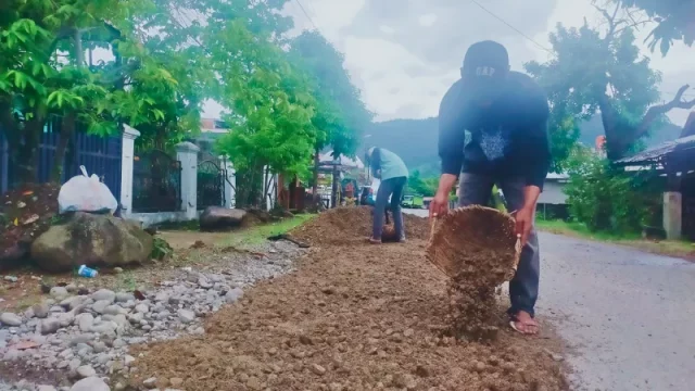Pekerja DPUPR Padang melakukan penambalan jalan berlubang dengan aspal