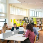 Sekelompok mahasiswa belajar bersama di meja perpustakaan kampus