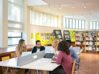 Sekelompok mahasiswa belajar bersama di meja perpustakaan kampus