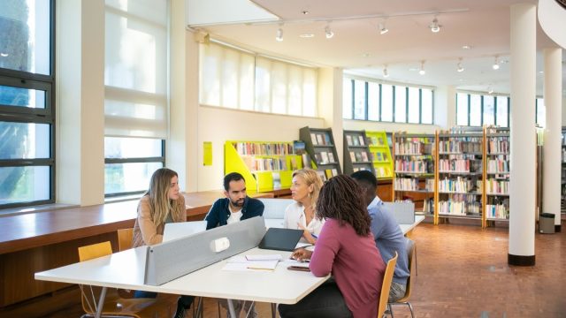 Sekelompok mahasiswa belajar bersama di meja perpustakaan kampus