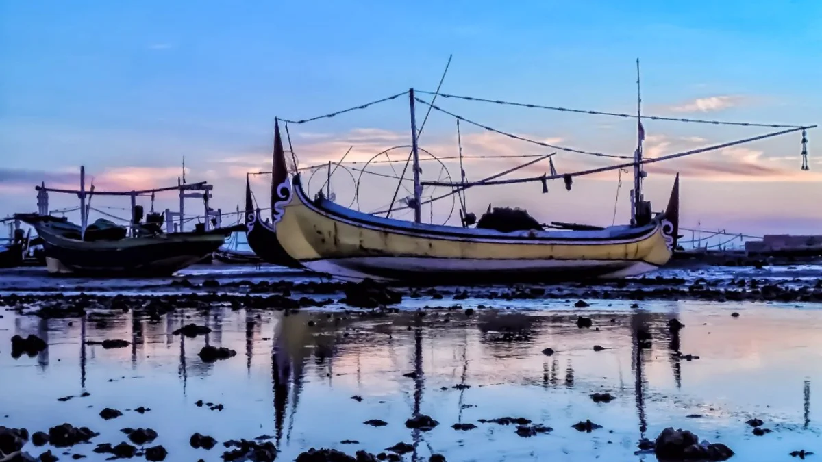 Perahu jukung nelayan tertambat di tepi pantai pada sore hari