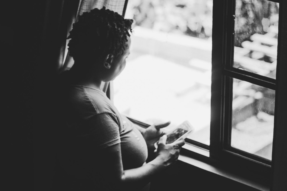 Seorang perempuan duduk sendiri di dekat jendela