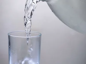 Air dituangkan dari ceret ke dalam sebuah gelas bening