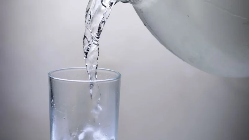 Air dituangkan dari ceret ke dalam sebuah gelas bening