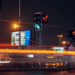 Papan-papan iklan menyala di persimpangan jalan kota pada malam hari