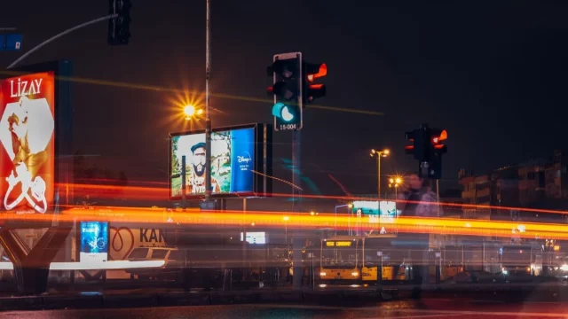 Papan-papan iklan menyala di persimpangan jalan kota pada malam hari