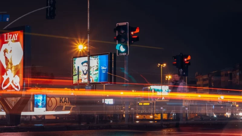 Papan-papan iklan menyala di persimpangan jalan kota pada malam hari