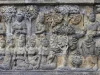 Panil relief batu Borobudur memuat banyak sosok manusia duduk berjajar di bawah pohon
