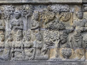 Panil relief batu Borobudur memuat banyak sosok manusia duduk berjajar di bawah pohon