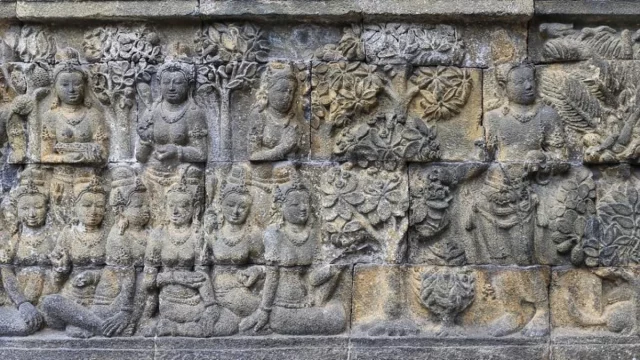 Panil relief batu Borobudur memuat banyak sosok manusia duduk berjajar di bawah pohon