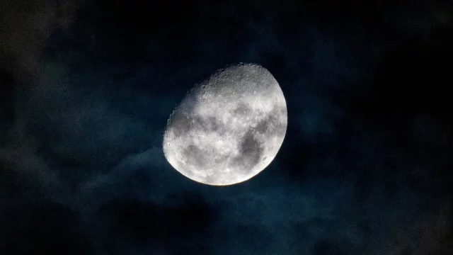 Bulan bersinar di balik lapisan awan tipis pada langit malam