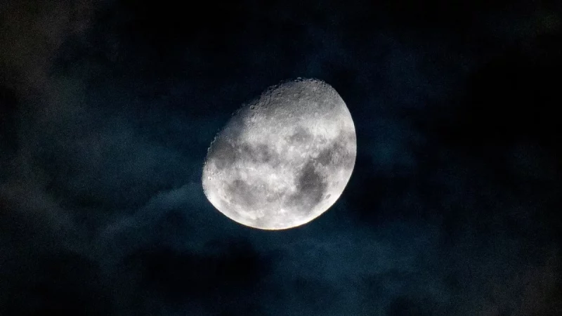 Bulan bersinar di balik lapisan awan tipis pada langit malam