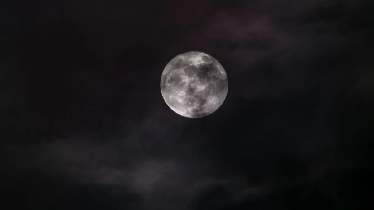 Bulan purnama tampak di antara awan pada langit malam