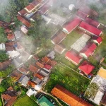 Pemandangan udara perkampungan beratap merah yang tertutup kabut tipis