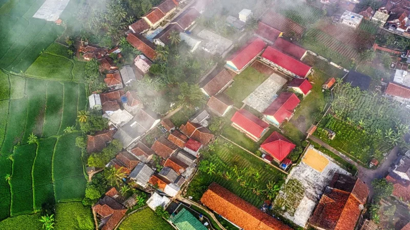 Pemandangan udara perkampungan beratap merah yang tertutup kabut tipis