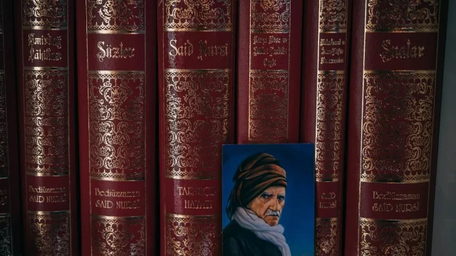 Deretan jilid kitab Risale-i Nur berjajar di rak dengan potret kecil di depannya