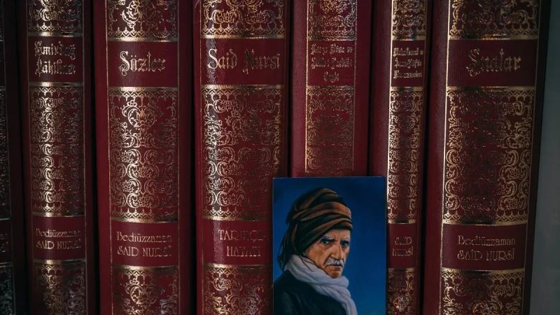 Deretan jilid kitab Risale-i Nur berjajar di rak dengan potret kecil di depannya