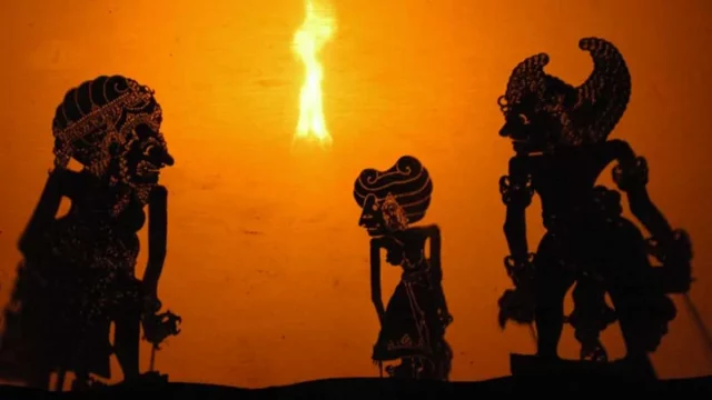 Siluet tokoh kera dalam pertunjukan wayang kulit di depan layar