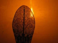 Siluet gunungan wayang kulit di depan layar yang disinari lampu