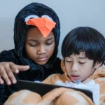 Dua anak menonton tayangan di layar tablet