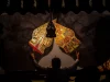 Dalang memainkan wayang kulit di depan kelir dalam sebuah pertunjukan