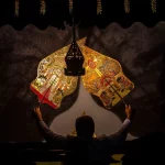 Dalang memainkan wayang kulit di depan kelir dalam sebuah pertunjukan