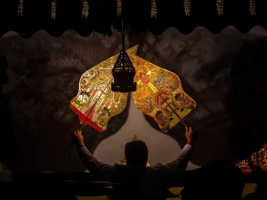Dalang memainkan wayang kulit di depan kelir dalam sebuah pertunjukan