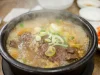 Semangkuk sup daging panas khas Korea dalam mangkuk batu, ditaburi irisan daun bawang