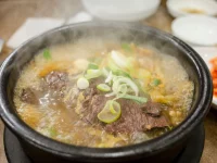 Semangkuk sup daging panas khas Korea dalam mangkuk batu, ditaburi irisan daun bawang
