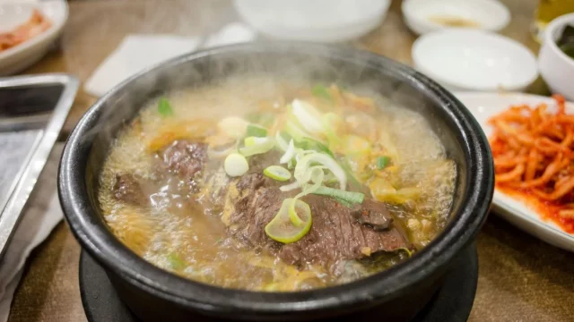 Semangkuk sup daging panas khas Korea dalam mangkuk batu, ditaburi irisan daun bawang
