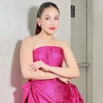 Ayu Ting Ting mengenakan gaun tanpa tali berwarna fuchsia berdiri di lorong studio