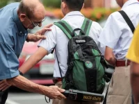 Guru memeriksa tas murid dengan detektor logam di sebuah sekolah di Bangkok