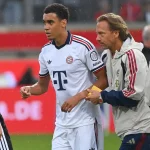 Jamal Musiala meninggalkan lapangan didampingi ofisial Bayern Munich. [Foto: Getty Images]