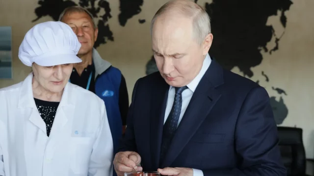 Presiden Rusia Vladimir Putin mencicipi produk saat mengunjungi kompleks pengolahan ikan di Pulau Iturup, Kepulauan Kuril. [Foto: AP]