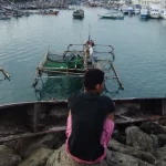 Perahu-perahu nelayan bersandar rapat di perairan pelabuhan.
