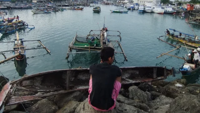 Perahu-perahu nelayan bersandar rapat di perairan pelabuhan.