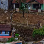 Deretan rumah warga berdinding kayu dan beton di permukiman menanjak dengan jalan setapak sempit