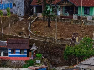 Deretan rumah warga berdinding kayu dan beton di permukiman menanjak dengan jalan setapak sempit
