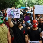 Pendukung Cockroach Janta Party mengenakan topeng dan membawa poster dalam unjuk rasa di Jantar Mantar, New Delhi.