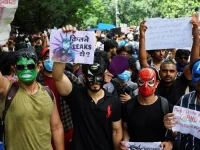 Pendukung Cockroach Janta Party mengenakan topeng dan membawa poster dalam unjuk rasa di Jantar Mantar, New Delhi.