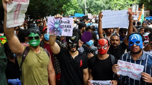 Pendukung Cockroach Janta Party mengenakan topeng dan membawa poster dalam unjuk rasa di Jantar Mantar, New Delhi.