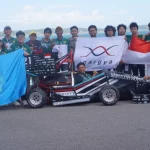 Anggota tim Anargya ITS berfoto bersama mobil balap listrik sambil membentangkan bendera Merah Putih dan panji kampus