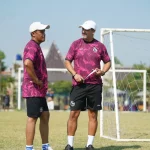 Doni Suherman berbincang bersama staf kepelatihan Arema FC di lapangan latihan.