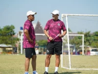 Doni Suherman berbincang bersama staf kepelatihan Arema FC di lapangan latihan.