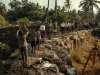 Ilustrasi warga dan pelajar berseragam berkumpul di dinding benteng batu kuno, seorang di antaranya mengangkat telepon genggam untuk memotret batu bertakik, dengan tripod alat ukur di dekatnya