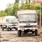 Iring-iringan truk bantuan kemanusiaan melintasi jalan yang rusak