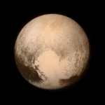 Planet katai Pluto berwarna kecokelatan dengan dataran es berbentuk hati di sisi bawah, dipotret wahana New Horizons