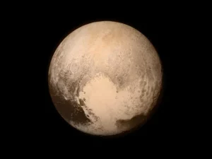 Planet katai Pluto berwarna kecokelatan dengan dataran es berbentuk hati di sisi bawah, dipotret wahana New Horizons