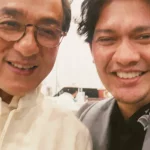 Tangkapan layar panggilan video memperlihatkan Jackie Chan dan Iko Uwais tersenyum